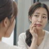 鏡を見てほうれい線を気にする30代女性