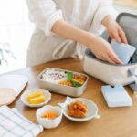 夏の朝に子どものお弁当と保冷バッグを準備する明るいキッチンイメージ