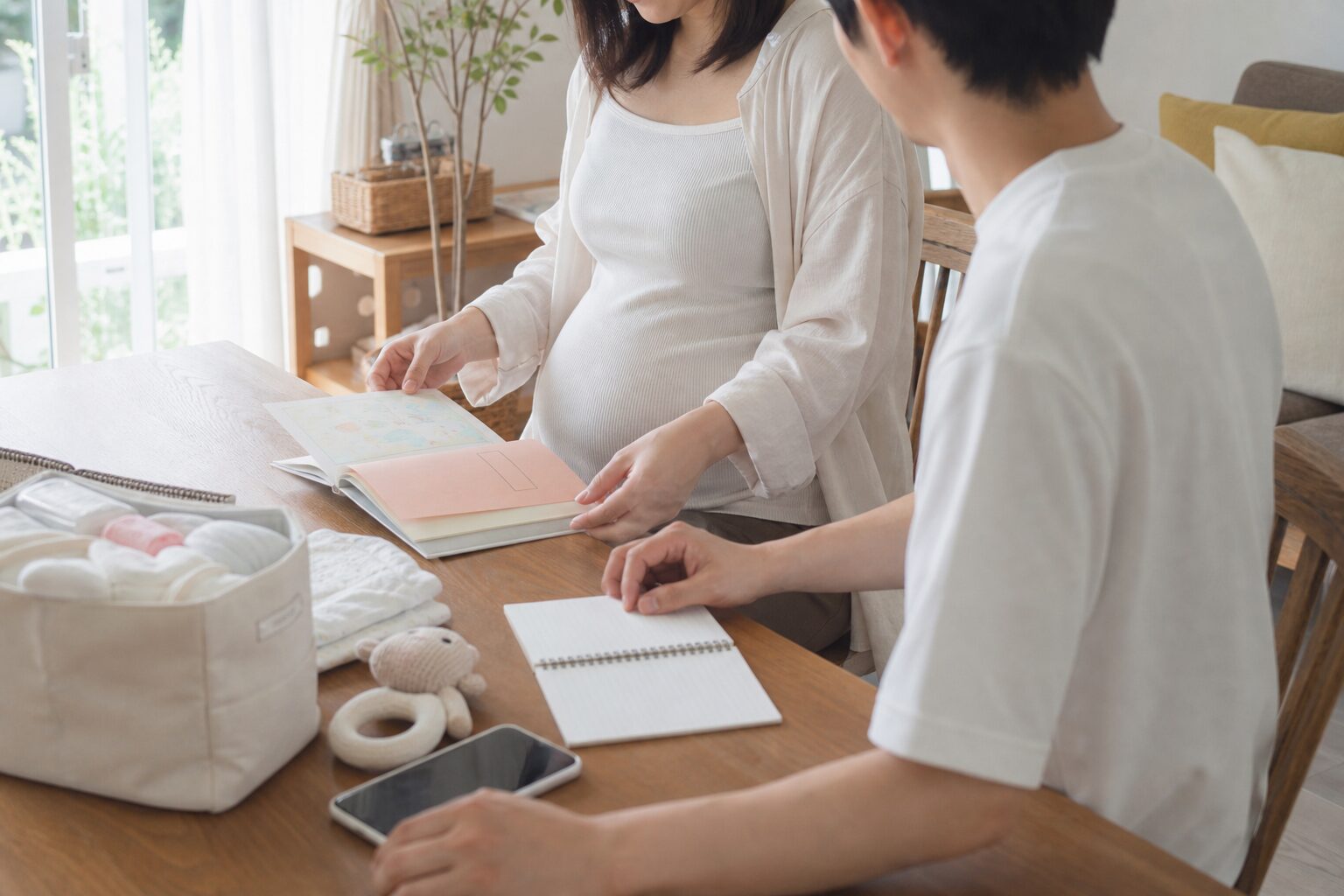 出産前に母子手帳や連絡メモをまとめて準備する妊婦と家族のイメージ