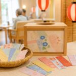 高齢者施設の夏祭りでおみくじ箱と和紙の短冊を並べたあたたかいイメージ