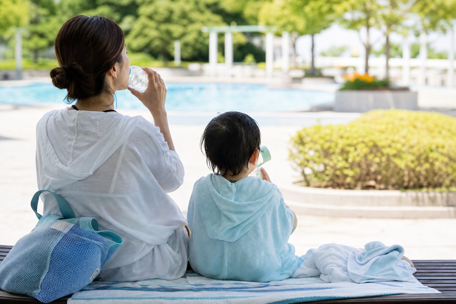 水遊びのあとに日陰で親子が水を飲みながら落ち着いて休むイメージ