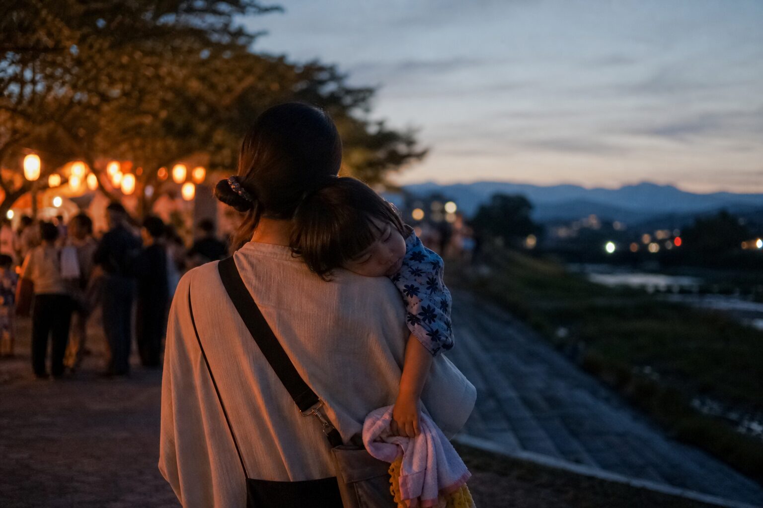 夏祭りの帰り道に眠くなった子どもを抱えて帰るイメージ