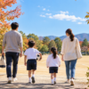 秋の公園の運動場へ歩いて向かう家族