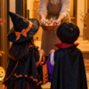 ハロウィンの仮装をした子どもたちが玄関でお菓子を受け取る様子