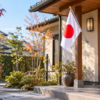 秋の朝の日本家屋の玄関に小さな国旗を掲げた様子